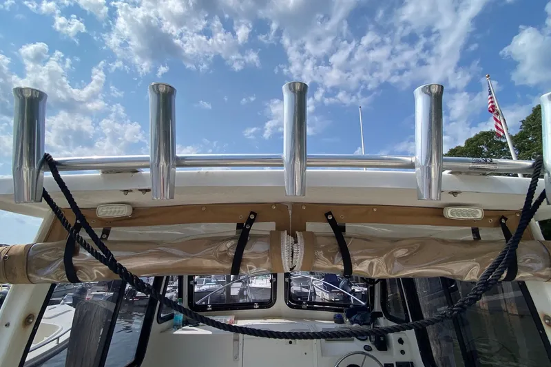 Slide: The Image of 2017 Eastern 22 Sisu Hardtop boat with rod holders under a partly cloudy sky. - 14