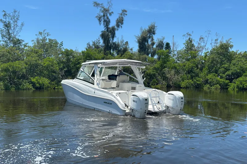 Slide: The Image of 2027 World Cat 325 DC boat cruising on a calm river with lush greenery. - 5