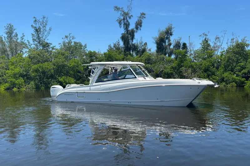 The Image of World Cat 325 DC 2027 boat on calm water with lush greenery background. - 0