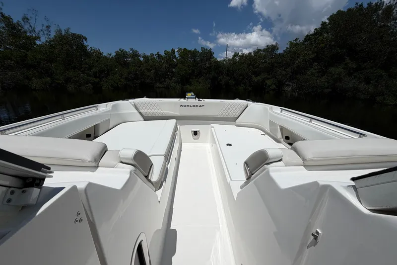 Slide: The Image of 2027 World Cat 325 DC boat interior with white seating and lush greenery backdrop. - 18