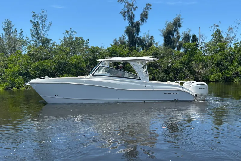 Slide: The Image of 2027 World Cat 325 DC boat cruising on a calm river with lush greenery. - 4