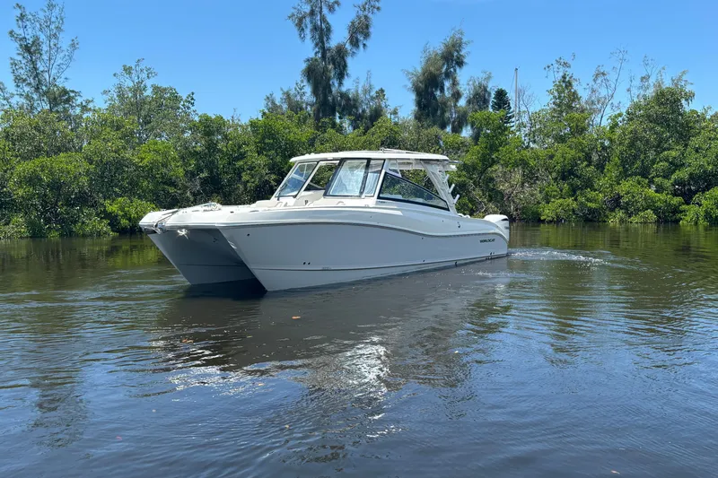 Slide: The Image of 2027 World Cat 325 DC boat cruising on a calm river surrounded by lush greenery. - 3