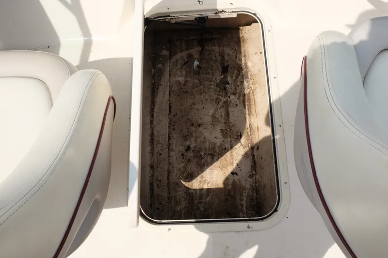 Slide: The Image of Open storage compartment on a 2009 Bryant 190 boat, between two white seats. - 15
