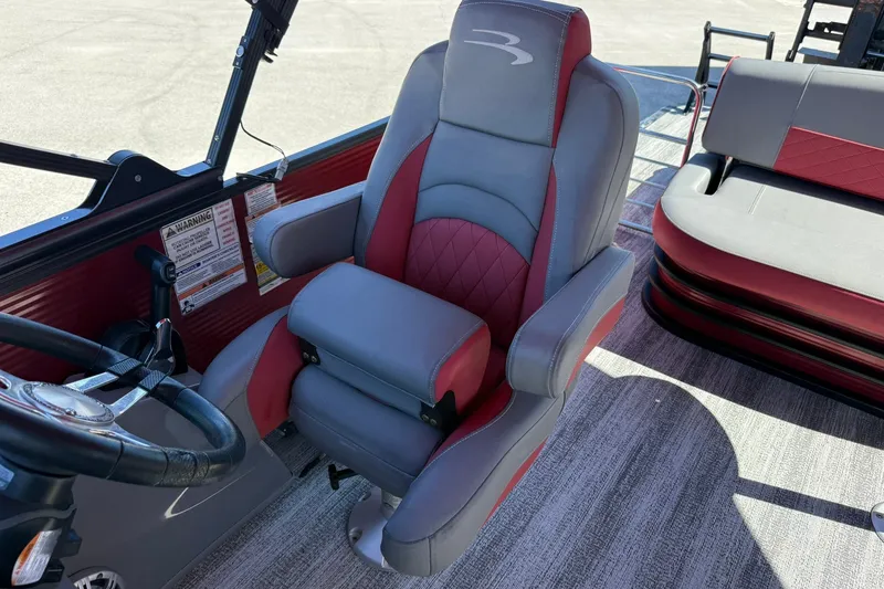 Slide: The Image of 2020 Bennington SXP 25 SSBXP boat interior with red and gray captain's chair. - 25