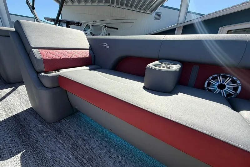 Slide: The Image of 2020 Bennington SXP 25 SSBXP boat interior with gray and red seating, cup holders, and speaker. - 32