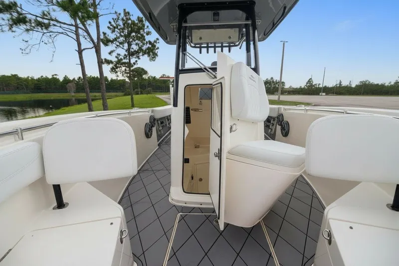 Slide: The Image of 2021 Cobia 280 Center Console boat interior with open storage compartment, white seating, and scenic background. - 13