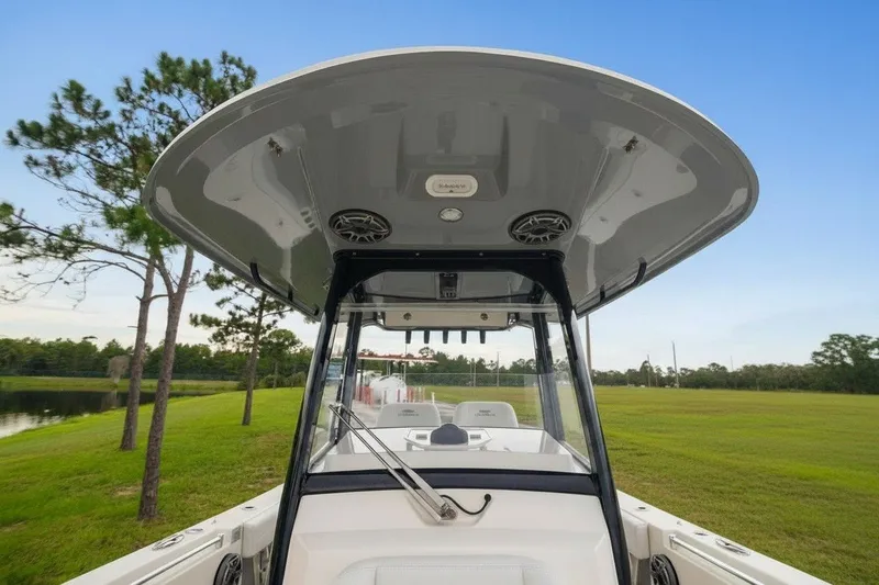 Slide: The Image of 2021 Cobia 280 Center Console boat with T-top, parked near a grassy field. - 19