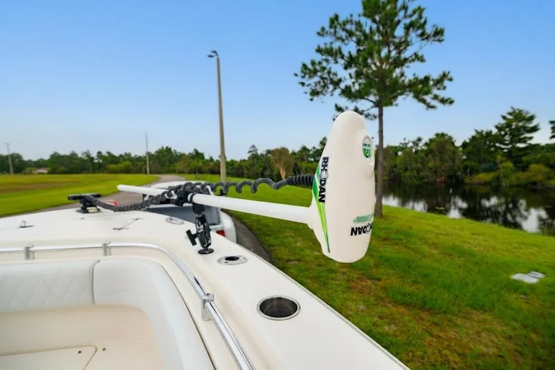 Slide: The Image of 2021 Cobia 280 Center Console boat with trolling motor near a scenic lake. - 15