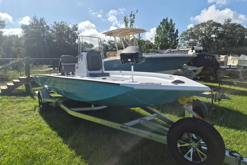 The Image of 2027 Xpress H20 Bay boat on trailer, parked on grass under a sunny sky. - 1