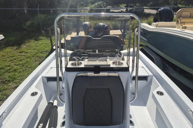 Slide: The Image of 2027 Xpress H20 Bay boat interior with console and seating, parked outdoors. - 19