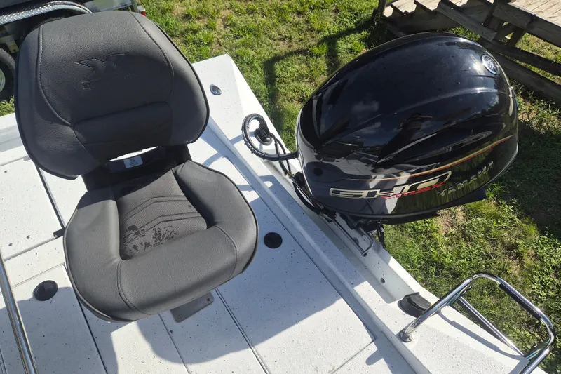 Slide: The Image of 2027 Xpress H20 Bay boat seat and engine detail on grassy background. - 5