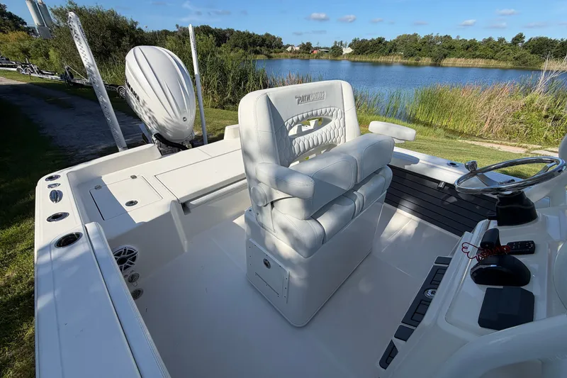 Slide: The Image of 2025 Pathfinder 2400 TRS boat interior with steering wheel, seating, and lake view. - 18
