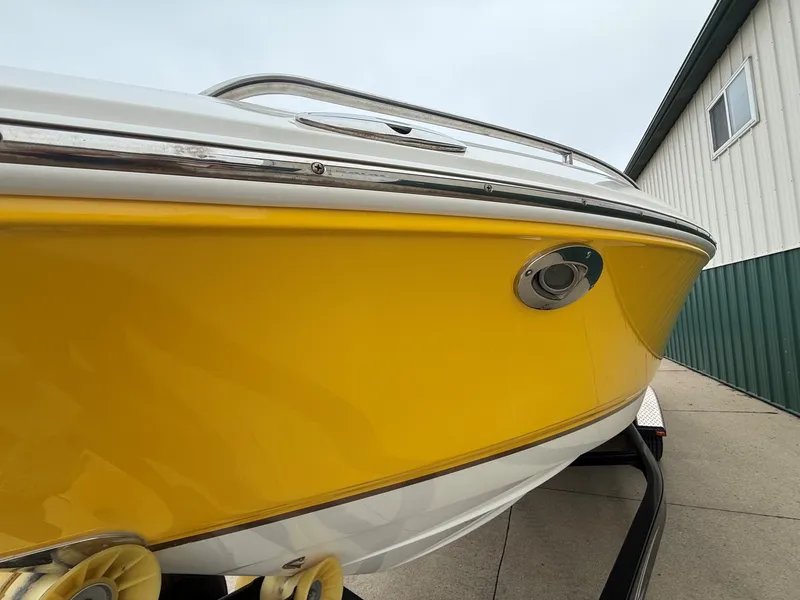 Slide: The Image of A yellow 2006 Chaparral SSi 256 boat on a trailer next to a building. - 2