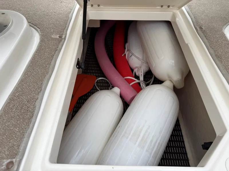 Slide: The Image of A storage compartment on a boat with white fenders and a red pool noodle. - 32