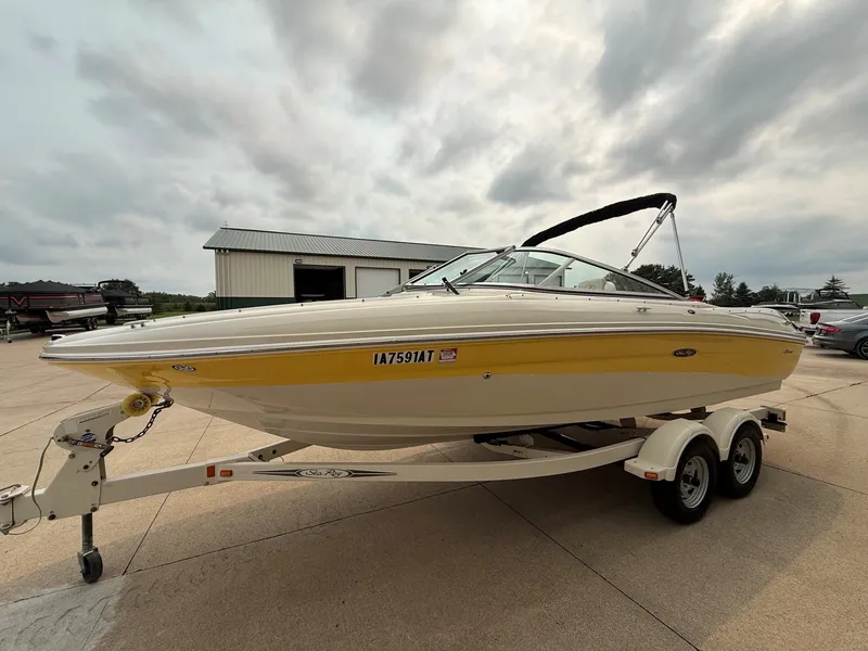 Slide: The Image of 2005 Sea Ray 200 Sport on a trailer, yellow and white paint, parked in an outdoor area. - 2