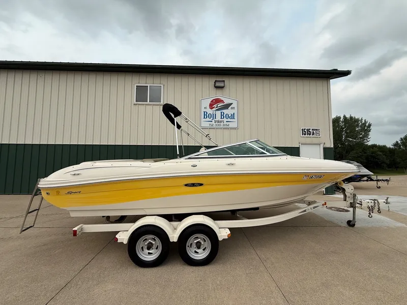 The Image of A yellow 2005 Sea Ray 200 Sport boat on a trailer in front of a building. - 0