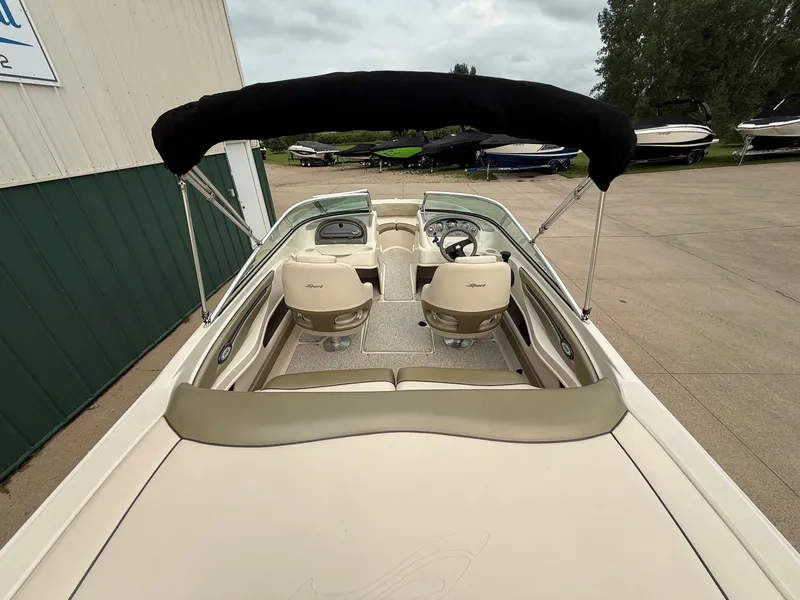 Slide: The Image of The image shows the cockpit of a 2005 Sea Ray 200 Sport with beige seats and a black bimini top. - 8