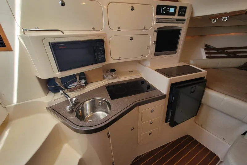 Slide: The Image of 2005 Grady-White Express 330 boat interior with kitchenette, sink, microwave, and compact appliances. - 23