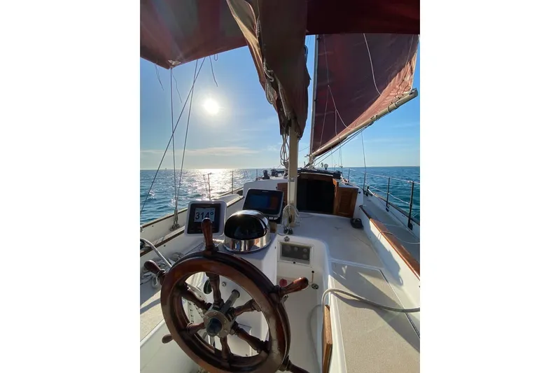 Slide: The Image of Sailing on a 1985 Nereia Yachts 38, sunlit ocean view, wooden helm in foreground. - 9