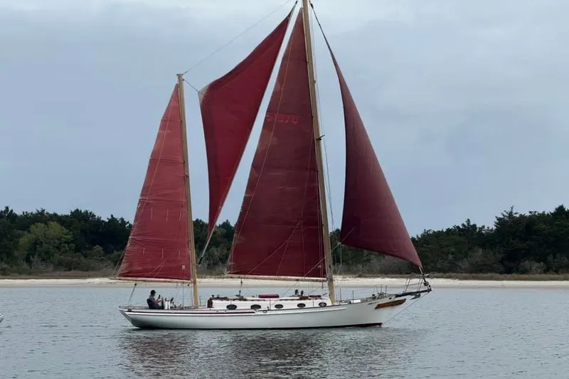 The Image of Classic 1985 Nereia Yachts 38 sailing on calm waters with red sails. - 0