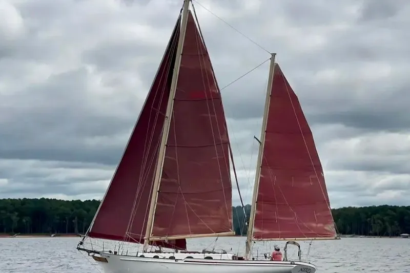 Slide: The Image of Sailing yacht Nereia 38 from 1985 with red sails on a cloudy day. - 2