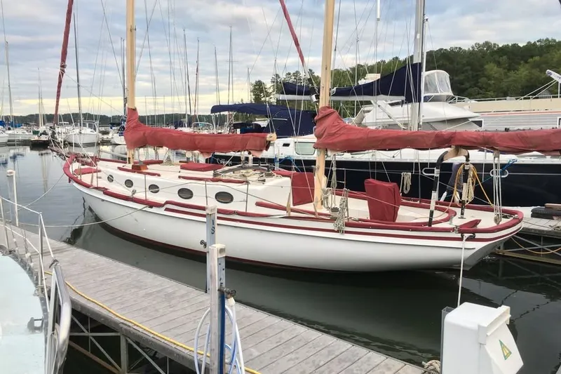 Slide: The Image of 1985 Nereia Yachts 38 sailboat docked in a marina, featuring red accents. - 7
