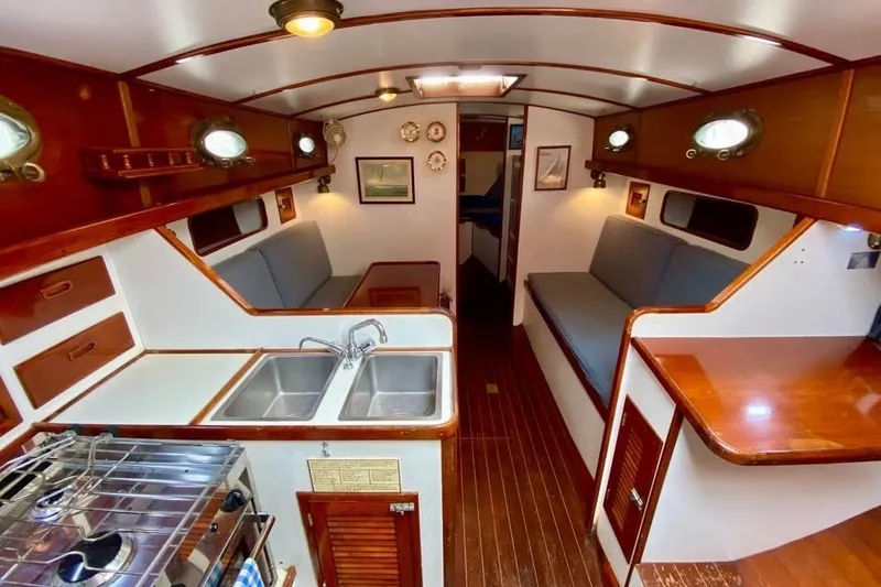 Slide: The Image of Interior of 1985 Nereia Yachts 38, featuring wood finishes and compact kitchen area. - 13
