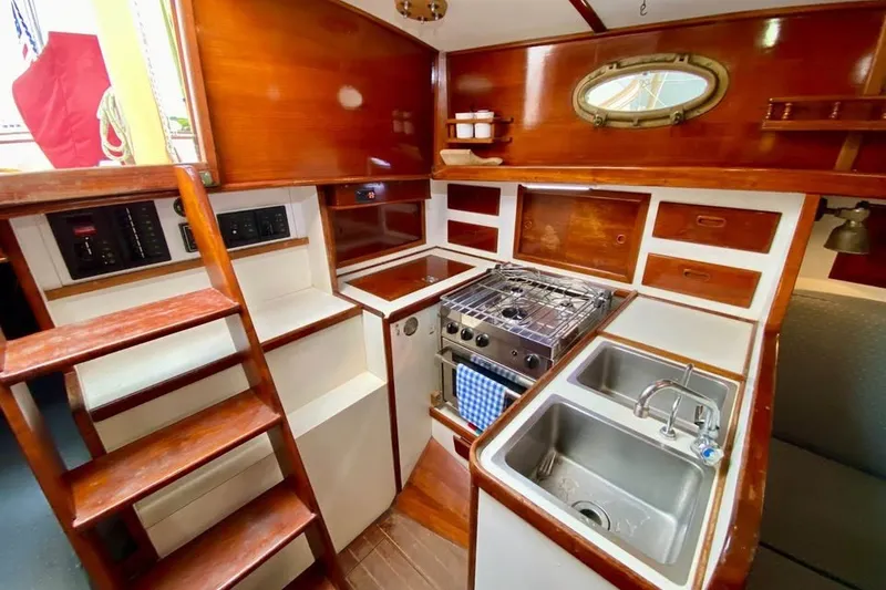 Slide: The Image of Interior of 1985 Nereia Yachts 38, featuring a compact kitchen with stove and sink. - 15