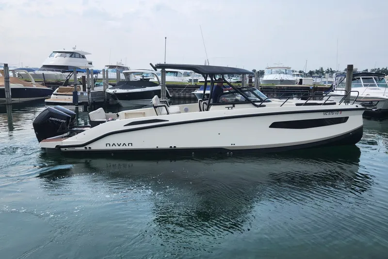Slide: The Image of 2025 Navan S30 boat docked in marina, featuring sleek design and Mercury outboard engine. - 2
