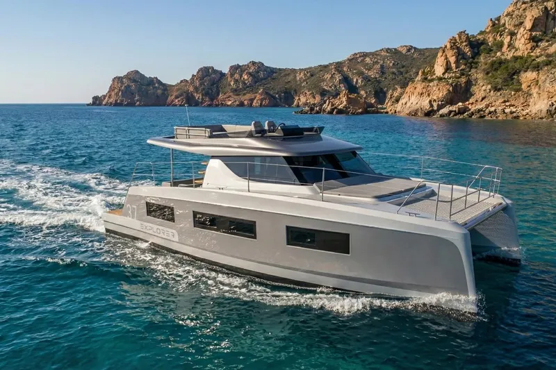 Slide: The Image of 2025 Aventura 37 Trawler cruising near rocky coastline in clear blue waters. - 10