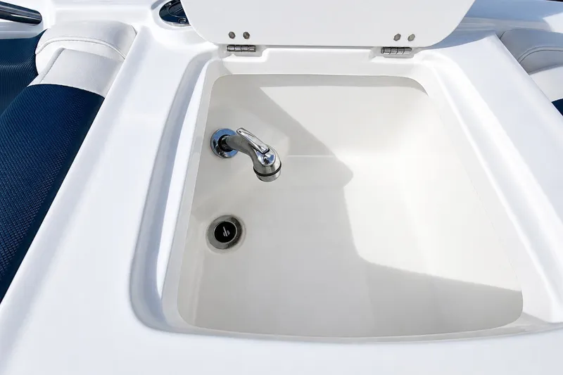 Slide: The Image of 2022 Tahoe 2150 boat sink with faucet and drain, featuring white and blue seating. - 22