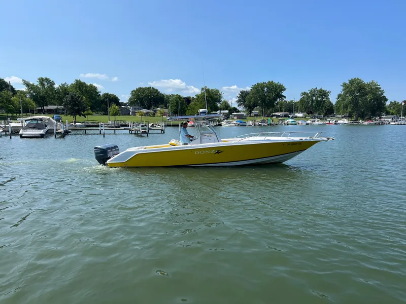 Slide: The Image of A yellow 2001 Donzi 352F boat on calm water, surrounded by trees and docks. - 2