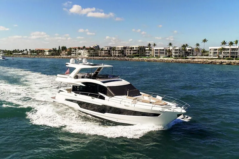 The Image of 2020 Galeon 680 Fly yacht cruising on a sunny day near coastal residences. - 0