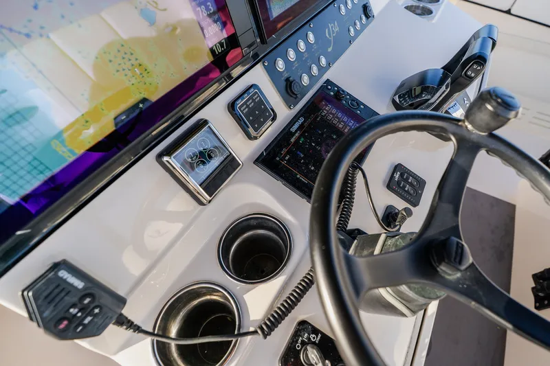 Slide: The Image of Boat cockpit with steering wheel, control panels, and navigation screens on a 2023 Young 34 model. - 33