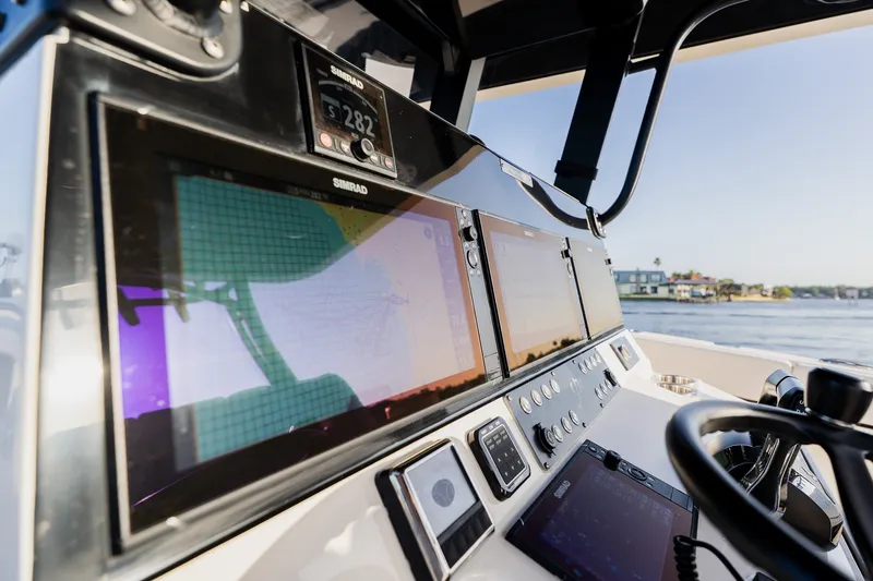 Slide: The Image of Boat dashboard with multiple Simrad displays, steering wheel, and water view, Young 34 model 2023. - 31