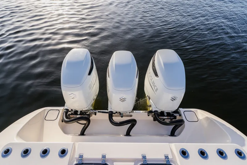 Slide: The Image of Triple outboard motors on a 2023 Young 34 boat, floating on calm water. - 48