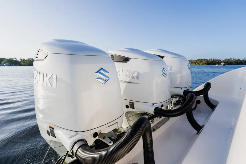Slide: The Image of Triple Suzuki outboard motors on a 2023 Young 34 boat, cruising on calm water. - 49