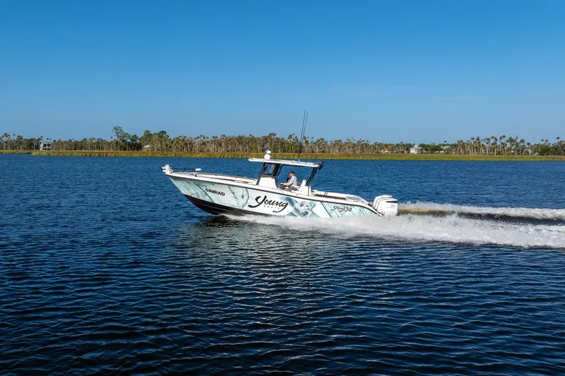 Slide: The Image of A 2023 Young 34 boat cruising on a calm lake under a clear blue sky. - 7