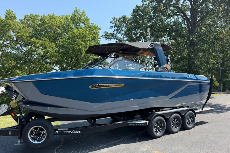 Slide: The Image of 2026 Nautique Super Air Nautique G25 boat on trailer, parked outdoors. - 2