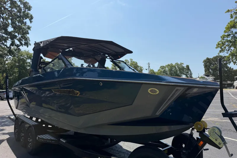 Slide: The Image of 2026 Nautique Super Air Nautique G25 boat on trailer in sunny parking lot. - 7