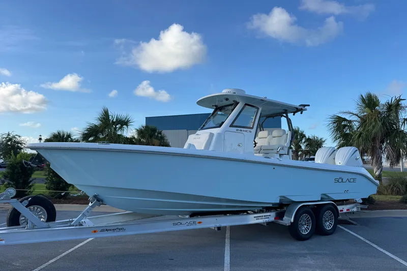 The Image of 2027 Solace 28HCS boat on trailer, parked outdoors under a clear blue sky. - 1