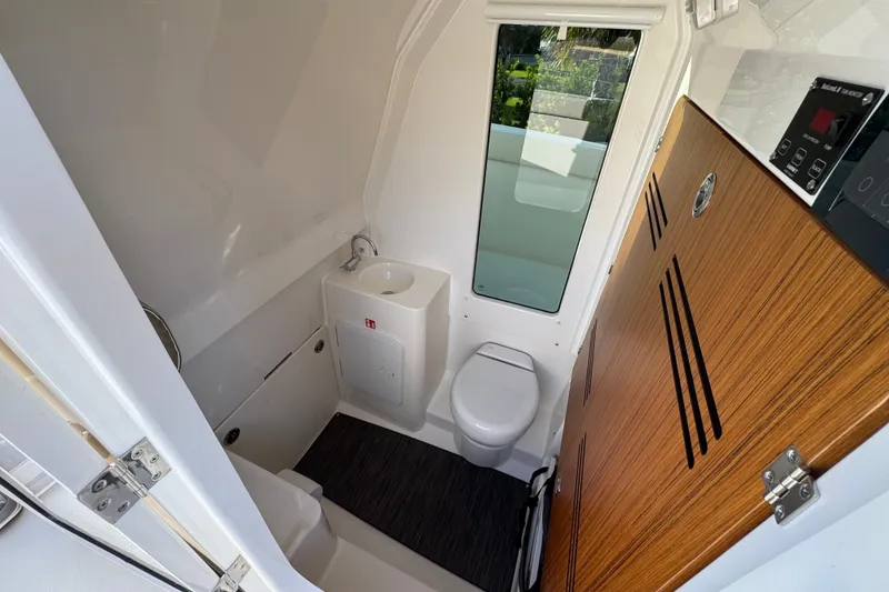 Slide: The Image of Modern bathroom interior in 2027 Solace 28HCS boat, featuring toilet, sink, and wooden accents. - 29