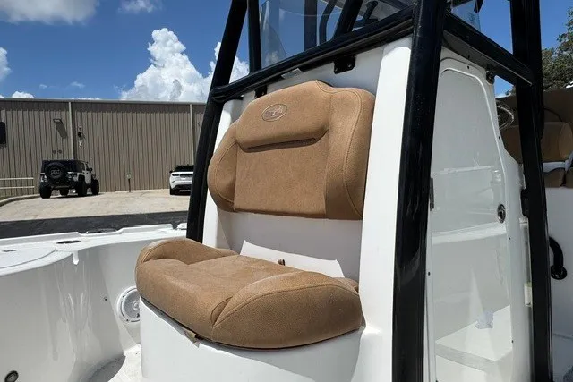 Slide: The Image of 2019 Sea Hunt BX22BR boat with tan cushioned seating and console, parked outdoors. - 16