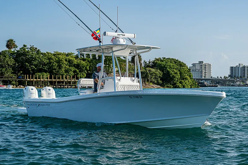 Slide: The Image of 2019 Ocean Master 296 boat cruising on blue water near lush shoreline. - 20