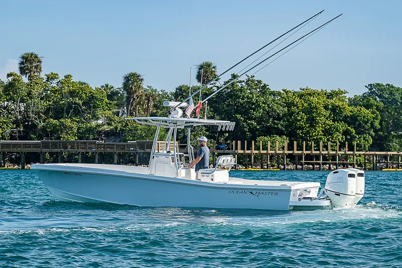Slide: The Image of 2019 Ocean Master 296 boat cruising on blue water near lush shoreline. - 21