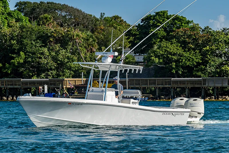 Slide: The Image of 2019 Ocean Master 296 boat cruising on water near lush shoreline. - 1