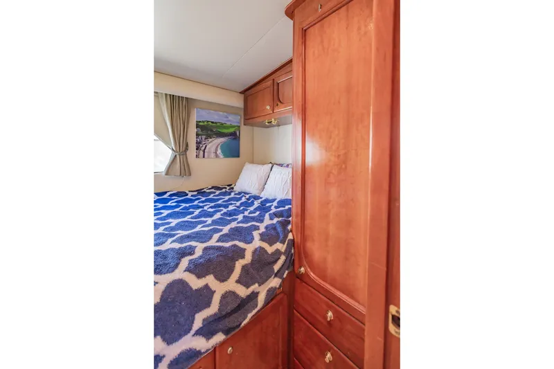 Slide: The Image of Cozy bedroom in 2003 Bluewater Yachts Custom 6000 with wooden cabinetry and nautical decor. - 50