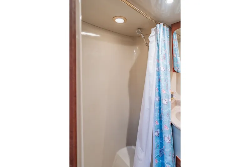 Slide: The Image of Shower area in 2003 Bluewater Yachts Custom 6000, featuring a blue patterned curtain. - 56
