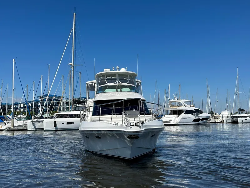 Slide: The Image of A 2003 Bluewater Yachts Custom 6000 docked in a marina, surrounded by other boats. - 3