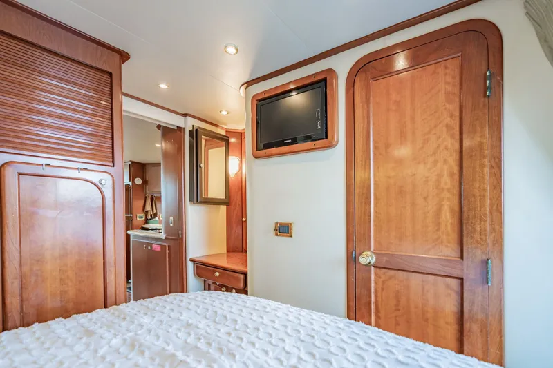 Slide: The Image of Luxurious 2003 Bluewater Yachts Custom 6000 cabin interior with wood finish and mounted TV. - 63